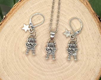 May include: A silver robot charm necklace and earrings set. The necklace and earrings feature a small robot charm with a heart on its chest and a star charm.