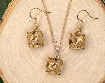 May include: A gold necklace and earrings set with a square-shaped, light amber-colored gemstone pendant and matching earrings.