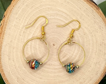 May include: Gold hoop earrings with a colorful glass bead dangle. The beads have a swirling pattern of blue, green, red, and gold.