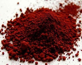 May include: A close-up of a pile of red iron oxide powder. The powder is a fine, granular material with a deep red color.