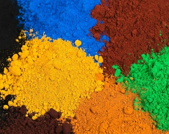 Puede incluir: Primer plano de cinco pigmentos en polvo de diferentes colores. Los colores son azul, amarillo, naranja, marrón y verde.
