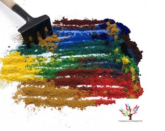 Puede incluir: Un pequeño rastrillo de jardín se utiliza para extender líneas de polvo de pigmento de colores en tonos de amarillo, verde, azul, rojo y marrón. El polvo está dispuesto en un patrón de arcoíris sobre una superficie blanca. El texto "YOURDAILYPIGMENTS" es visible en la esquina inferior derecha de la imagen.