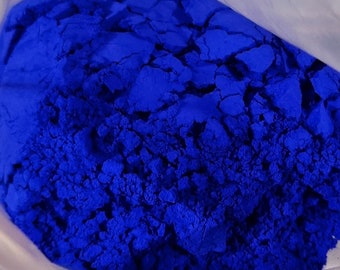 Puede incluir: Una vista cercana de una bolsa llena de un polvo azul brillante. El polvo está finamente molido y tiene una textura ligeramente granulada.