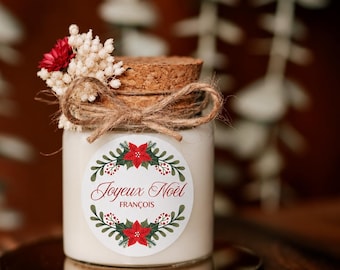 Può includere: Un barattolo di candela in vetro con coperchio in sughero, legato con un fiocco in corda di juta e decorato con fiori bianchi secchi e un piccolo fiore rosso. Un'etichetta circolare presenta una ghirlanda di stelle di Natale con il testo Joyeux Noël e FRANÇOIS.
