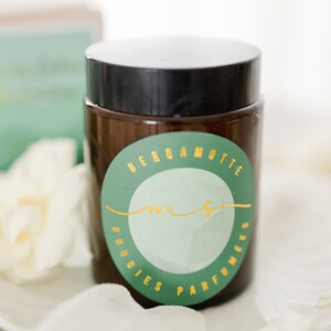 May include: A brown glass jar with a black lid and a green and gold label that says "Bergamotte Bougies Parfumees".