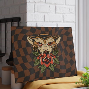 May include: A brown and black checkered background with a vintage illustration of a tiger's head with a red rose in its mouth. The tiger's head is surrounded by green leaves.