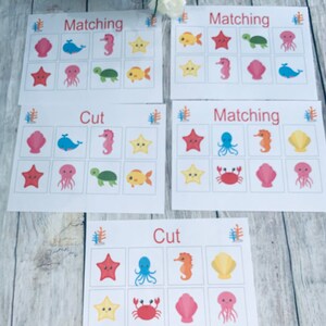 Peut inclure: Quatre cartes de jeu imprimables sur le thème de la vie marine. Les cartes sont intitulées "Matching" et "Cut". Les cartes présentent des images d'une étoile de mer, d'une pieuvre, d'un hippocampe, d'une coquille, d'un crabe, d'une tortue et d'un poisson.