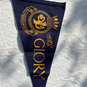 May include: A navy blue felt pennant with gold lettering that reads "HMS GLORY" and a gold crest with the words "PER CONCORDIAM GLORIA" and "GLORY".