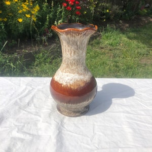 May include: A brown and white ceramic vase with a scalloped rim. The vase has a mottled glaze with brown and white streaks.