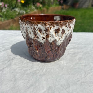 May include: A brown and white ceramic planter with a textured surface. The planter has a white glaze with brown accents.
