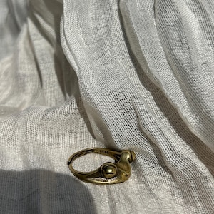 May include: A gold-toned metal ring featuring a stylised frog design with two prominent eyes on the band. The ring has a smooth, polished finish and includes a small stamp on the inner surface that reads 925, indicating its sterling silver composition.