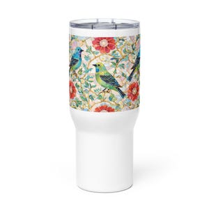 Puede incluir: Vaso de viaje blanco con un diseño floral y de pájaros colorido. El patrón presenta flores rojas, hojas verdes y pájaros azules y verdes. El vaso tiene una base blanca y una tapa plateada.