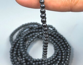 May include: A black hematite beaded bracelet with small, round beads. The bracelet is shown wrapped around a finger.