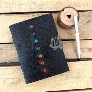 May include: Black leather journal with a five-pointed star design and a lock. The star is adorned with seven colorful gemstones.