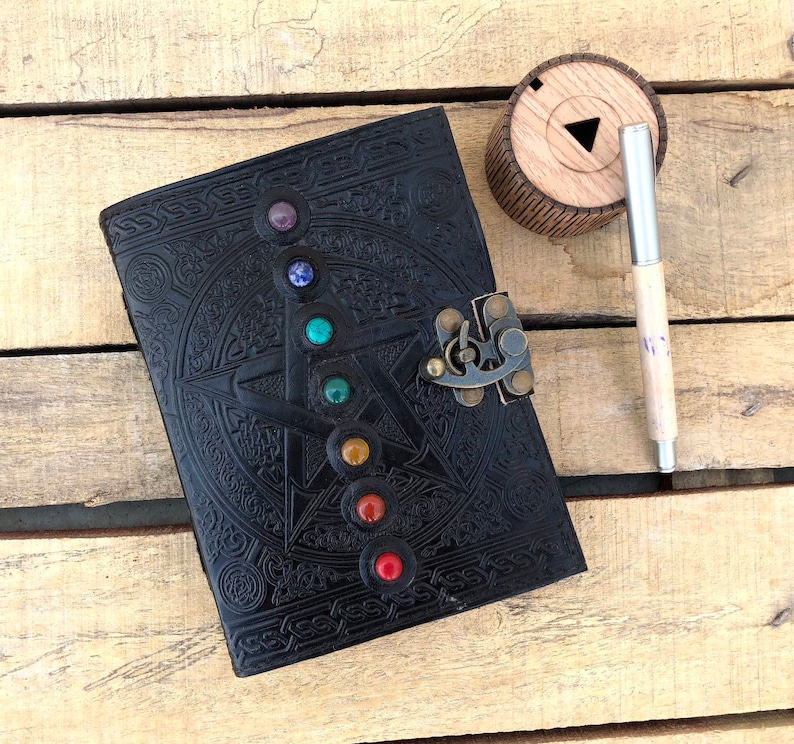 May include: Black leather journal with a five-pointed star design and a lock. The star is adorned with seven colorful gemstones.