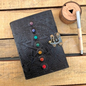 May include: Black leather journal with a pentacle design and a brass lock. The journal has seven colorful gemstones embedded in the pentacle design.