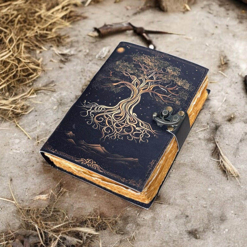 May include: A black leather journal with a gold tree design and a brass clasp. The journal has a distressed look and is perfect for writing down your thoughts and ideas.