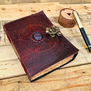 May include: A red leather journal with a pentagram design and a brass clasp. The journal has a decorative, aged look and is perfect for writing or keeping secrets.