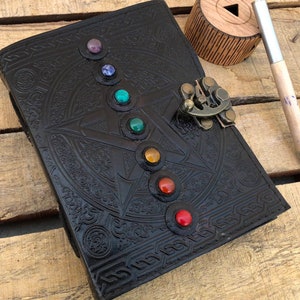 May include: Black leather journal with a pentagram design and colorful gemstones around the edges. The journal has a brass lock and clasp.