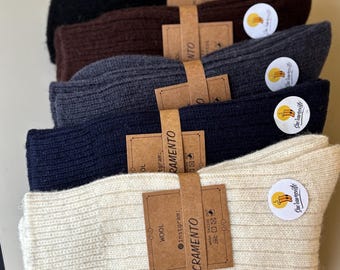 May include: A stack of five pairs of wool socks in various colors: black, brown, gray, navy blue, and cream. Each pair is bundled with a brown paper band that reads "SACRAMENTO" and a small round sticker.