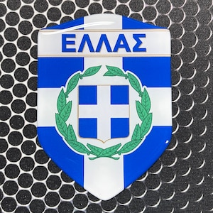 May include: A blue and white shield-shaped sticker with the Greek flag and the word "ΕΛΛΑΣ" in gold lettering.