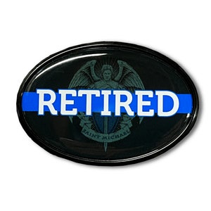 May include: Black oval car sticker with a blue line and the word "RETIRED" in white letters. The sticker features a graphic of an angel with wings and a sword.