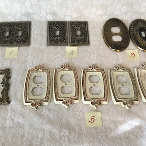 May include: Assortment of decorative light switch and outlet covers in various styles and finishes.  The covers are made of metal and plastic and feature ornate designs.  Some of the covers are gold, silver, and white.
