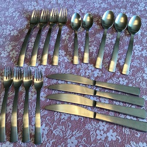 May include: A set of silverware with 8 forks, 8 spoons, and 8 knives. The silverware is made of stainless steel and has a polished finish.