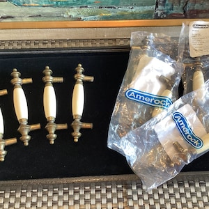 May include: Five antique brass cabinet knobs with white ceramic inserts. The knobs are packaged in plastic bags with the Amerock brand label.