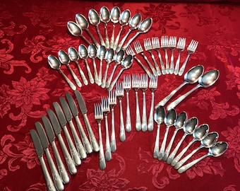 May include: A set of silverware, including forks, knives, and spoons, laid out on a red tablecloth. The silverware is made of silver and has a decorative pattern.