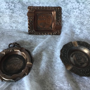 Price Is For The Set Of 3 Copper Ashtrays 1 New York united nations 2 Reno,Lake Taho, Virginia city 3 Empire State Bld. Trade Center,Liberty
