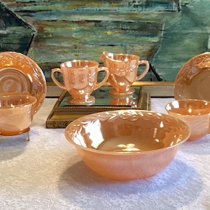May include: A set of vintage pink milk glass dishes with a floral design. The set includes a bowl, two cups and saucers, a creamer, and a sugar bowl.