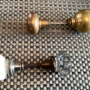May include: Three antique door knobs, one with a white porcelain knob, one with a clear glass knob, and one with a brass knob.