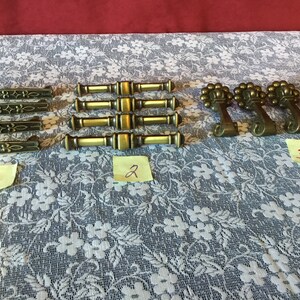 May include: Assortment of antique brass cabinet hardware, including drawer pulls and knobs. The pulls have a floral design and the knobs have a decorative scroll design.