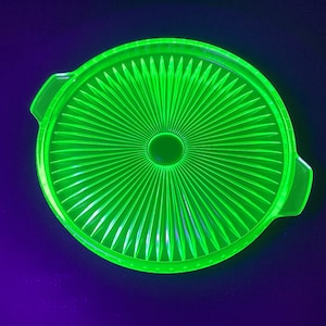 May include: A green glass serving dish with a fluted design. The dish has a round shape and a raised rim.