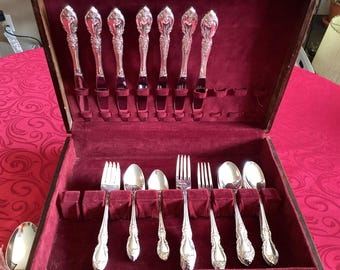 May include: A wooden box with a red velvet interior, containing a set of silver flatware. The flatware includes forks, spoons, and knives.