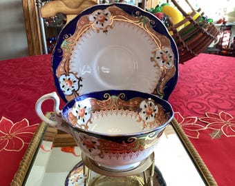 May include: A vintage teacup and saucer set featuring a blue and gold floral design. The cup and saucer are adorned with intricate details and a delicate floral pattern.
