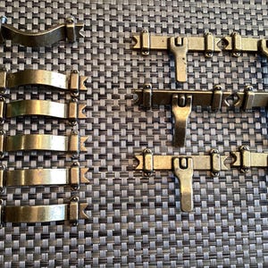 May include: A set of eight antique-style brass cabinet hardware pulls. Five are curved and three are straight with a decorative design.