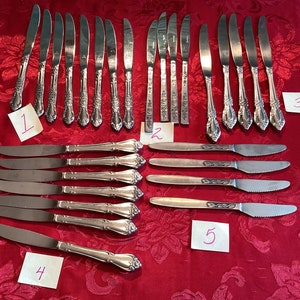 May include: A collection of 20 silver dinner knives, arranged in five rows of four knives each. The knives are labeled with numbers 1 through 5.