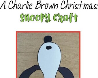 May include: A black and white paper craft of Snoopy from the Peanuts cartoon. Snoopy is wearing his signature red scarf and is standing on a wooden surface. The title "A Charlie Brown Christmas Snoopy Craft" is at the top of the image.