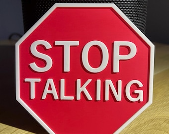 May include: A red octagonal sign with a white border and the words "STOP TALKING" in white. This decorative sign is likely for a home or office setting. The sign's design is clear and the message is easily understood.