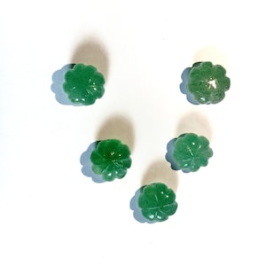 May include: Five green jade stone beads carved in the shape of a four-leaf clover.
