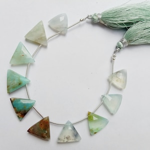 May include: Strand of triangular gemstone beads in shades of green, blue, and brown, strung on a silver wire. The beads are faceted, and the strand is accented with a mint green tassel.