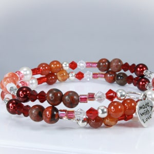 May include: A multi-strand bracelet with red, orange, and white beads, including a heart charm that says "Made with Love".