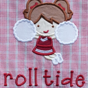 May include: Embroidered design of a cheerleader with brown hair, a red and white uniform, and white pom-poms. The text "roll tide" is embroidered in red on a red and white plaid background.