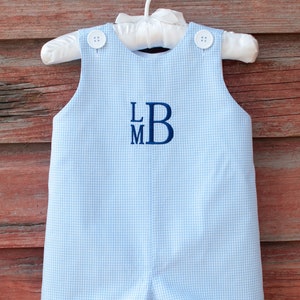 Peut inclure: Une barboteuse bébé en gingham bleu clair avec des boutons blancs et un monogramme brodé bleu marine "LMB".