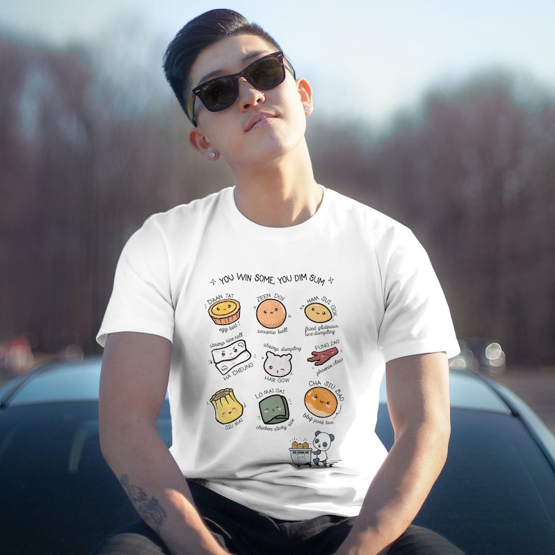 May include: White t-shirt with a graphic design of various dim sum dishes with their names in English and Chinese. The text at the top of the design reads "You win some, you dim sum."
