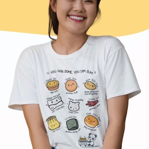 May include: A white t-shirt with a graphic of various dim sum dishes, each with a cute cartoon face. The text on the shirt reads "You win some you dim sum".