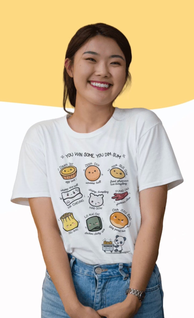 May include: A white t-shirt with a graphic of various dim sum dishes, each with a cute cartoon face. The text on the shirt reads "You win some you dim sum".