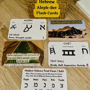 May include: A set of Hebrew Aleph-Bet flash cards. The cards feature ancient and modern Hebrew letters, along with their meanings and pictorial representations. The cards are designed for educational purposes.